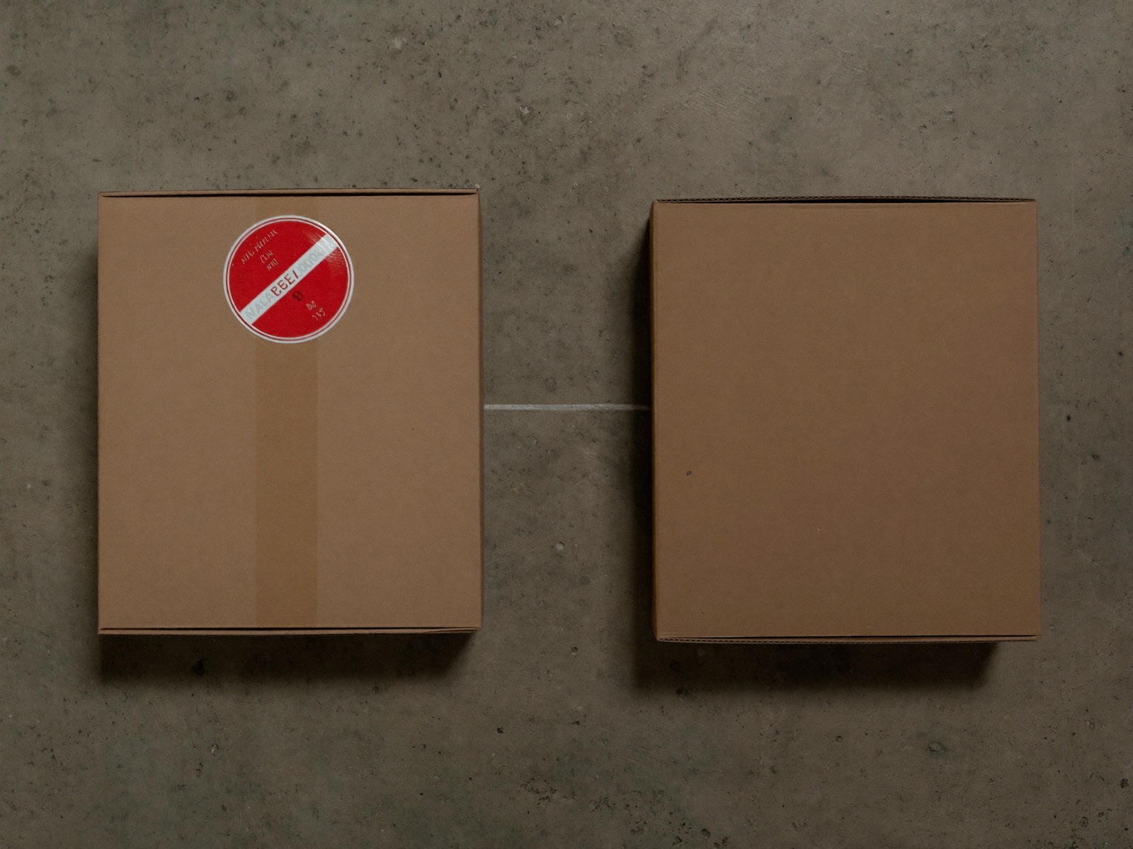 Two identical cardboard boxes, one marked with a red sticker